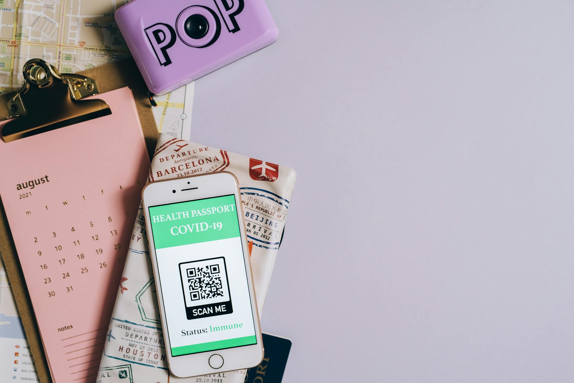 Flat lay image of a health passport with a COVID-19 QR code, calendar, and map.