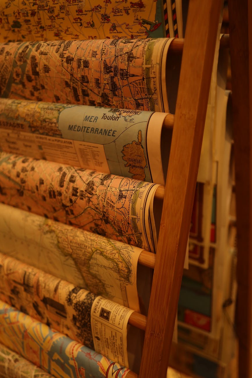 Various maps arranged neatly on a wooden rack, showcasing geographical details in warm lighting.