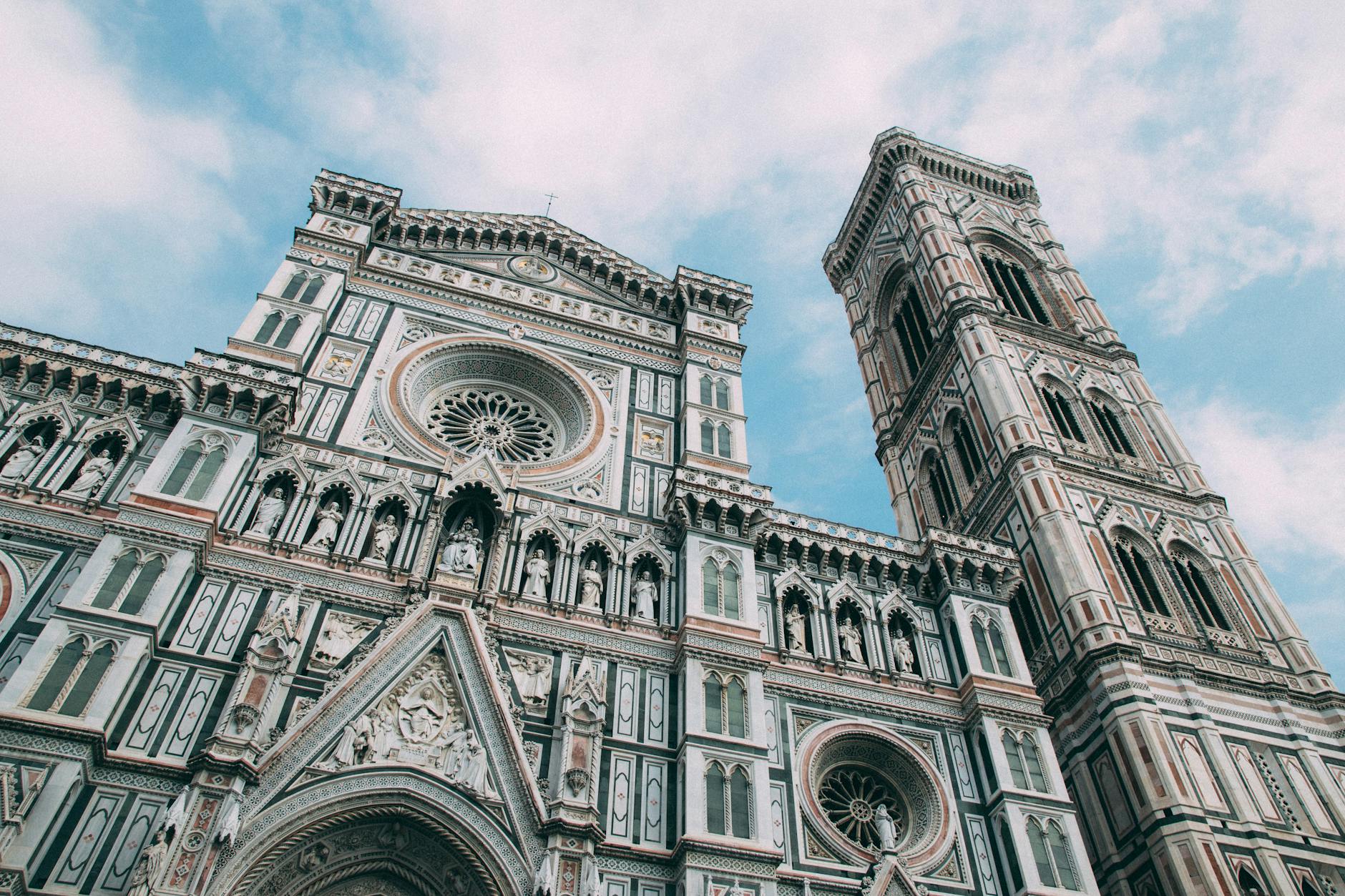Capture of the Florence Cathedral's ornate facade and bell tower against a blue sky in Italy.