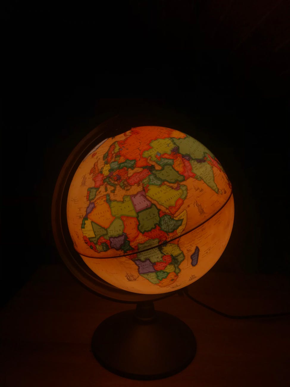 A glowing globe displaying continents and countries on a dark background.