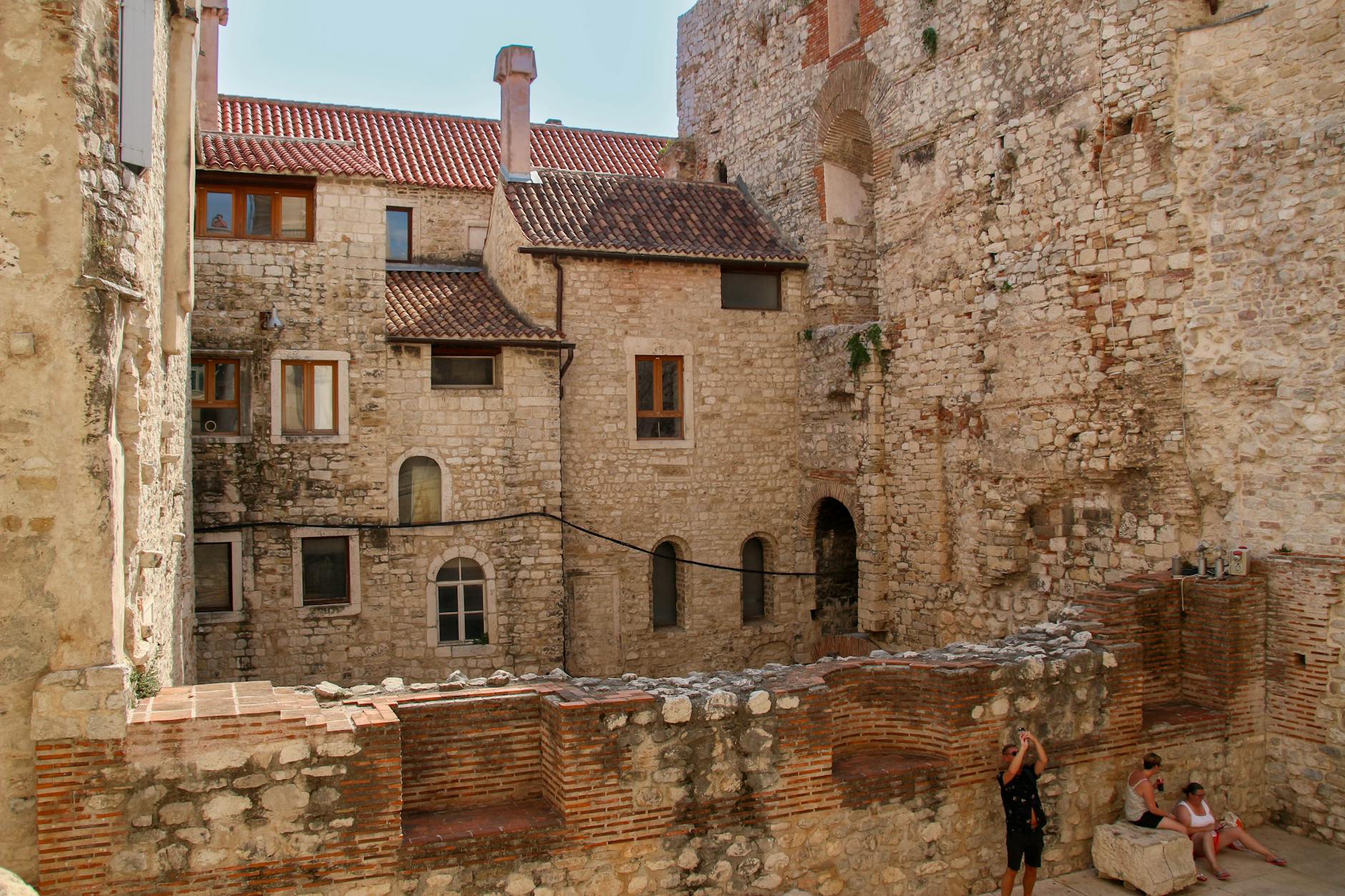 Ancient stone architecture with people in courtyard, capturing European historic vibes.