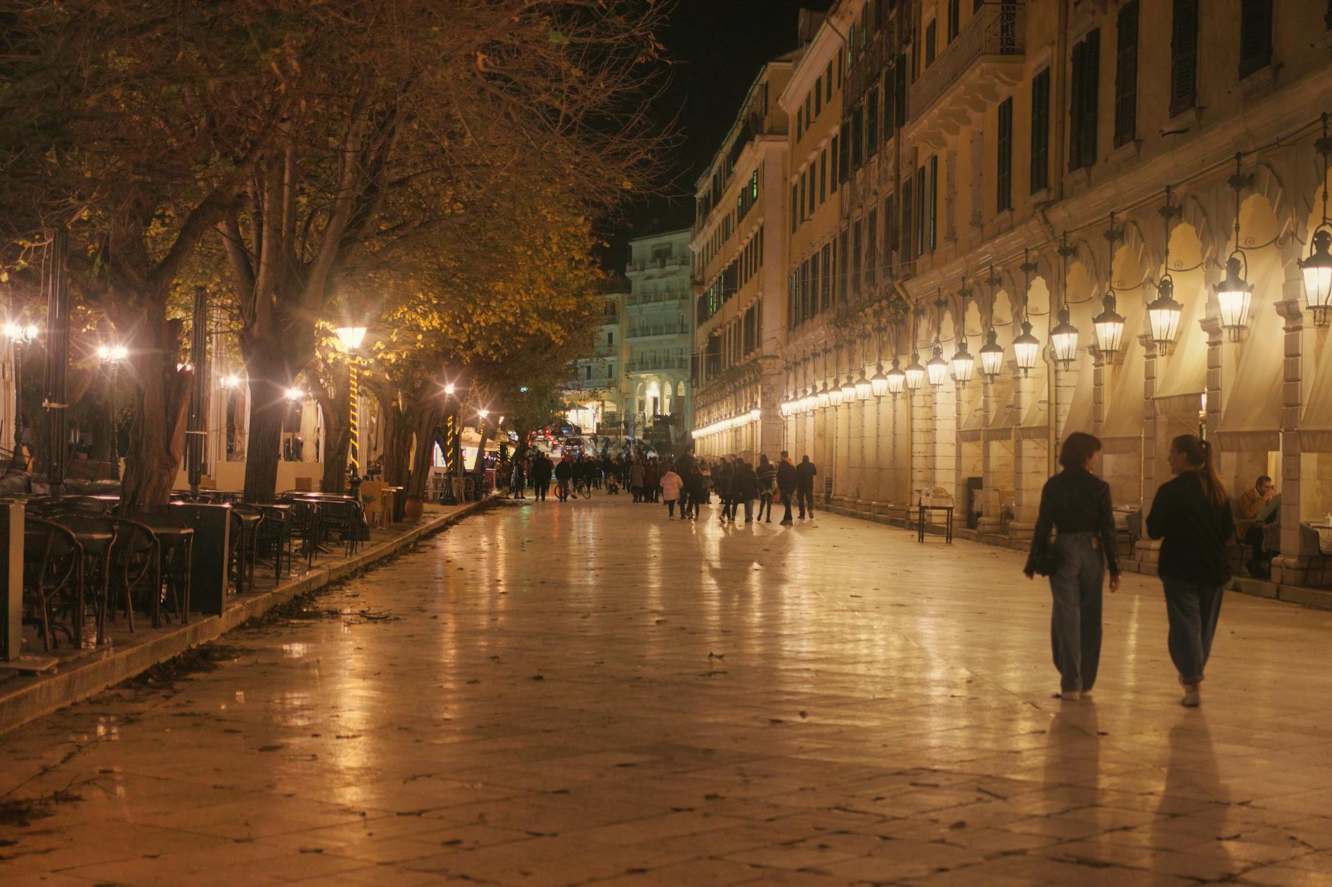 Liston Street in Corfu, Greece, elegantly lit at night with pedestrians strolling.