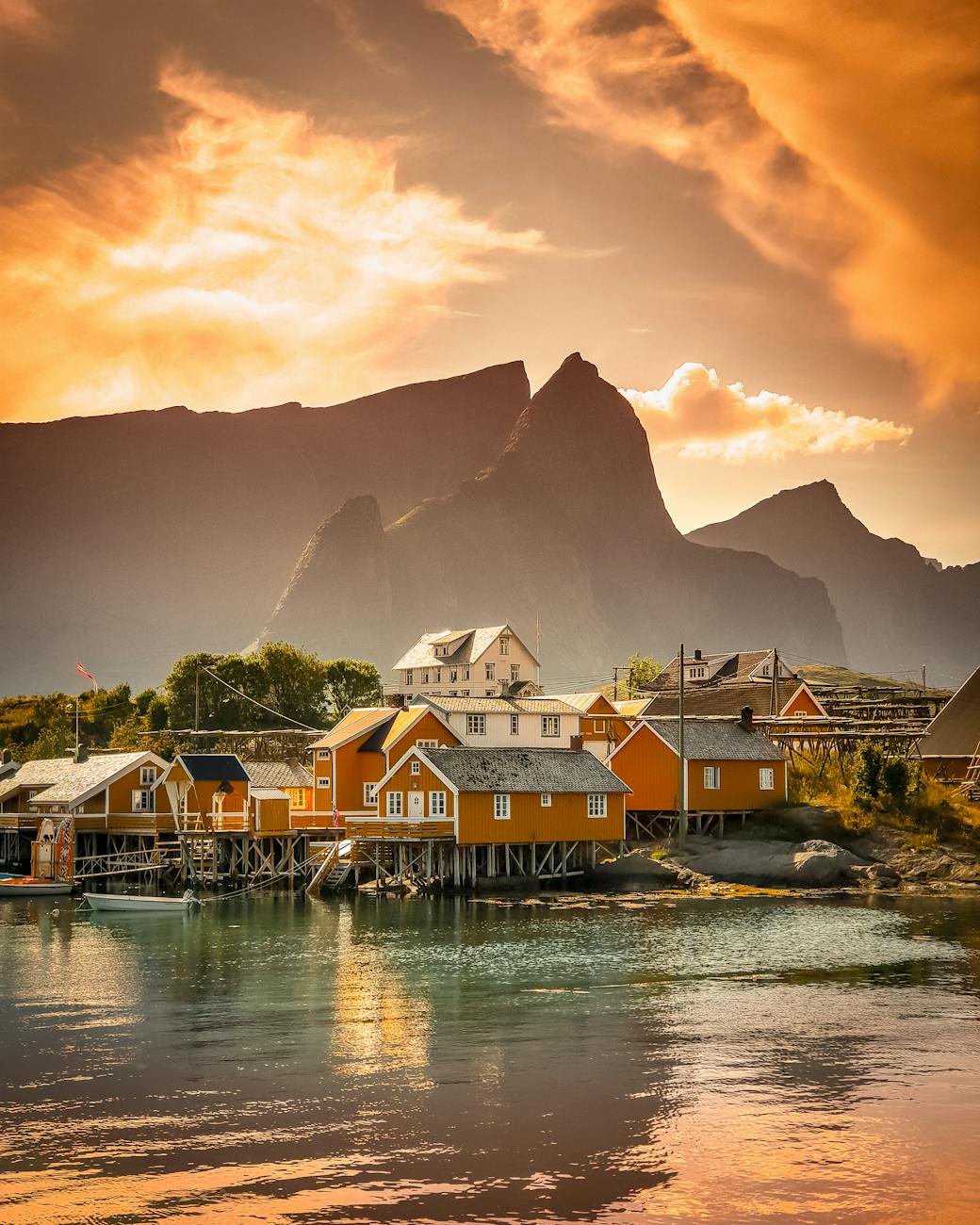 Scenic view of a colorful village by the fjord against a dramatic sunset in Vågan, Nordland, Norway.