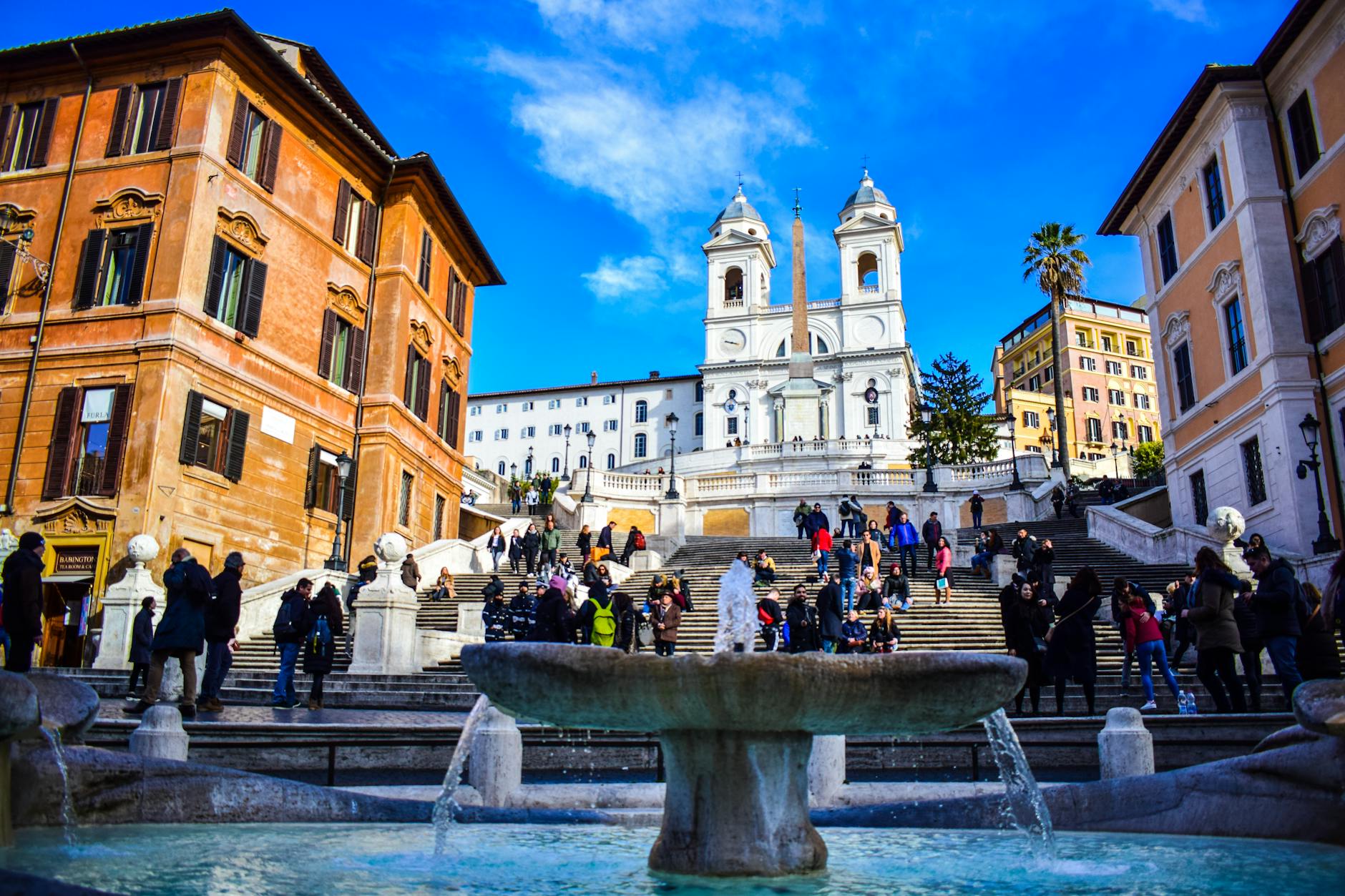 Tourists enjoying a sunny day at the iconic Spanish Steps in Rome, Italy.