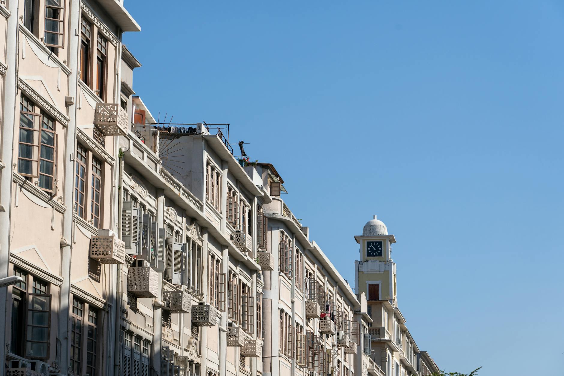 Beautiful perspective of historic buildings and clock tower against a bright clear blue sky.