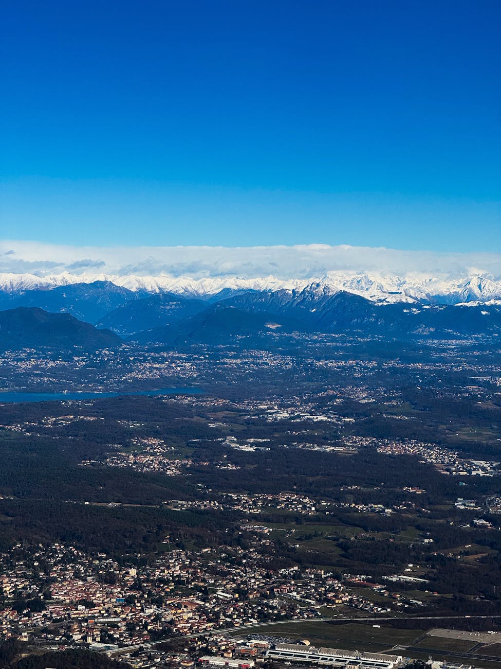 Stunning aerial view showcasing Lecco and the snow-capped Alps under a clear blue sky.