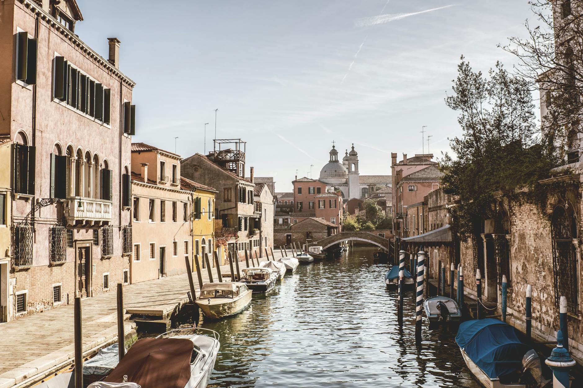 Explore the tranquil Venetian canal surrounded by historic buildings and picturesque boats.