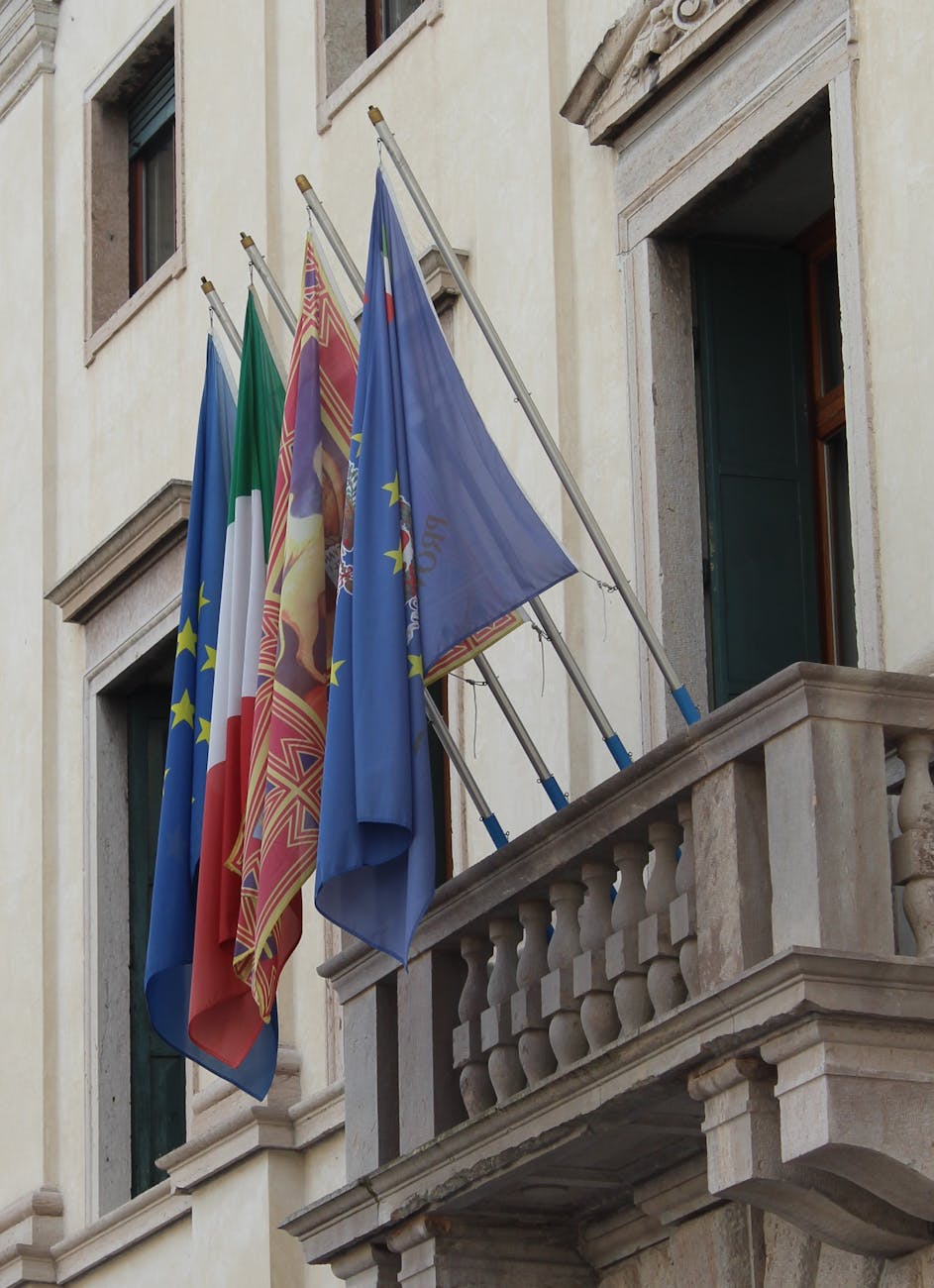 Colorful flags on a historic building's balcony, showcasing European and cultural representation.