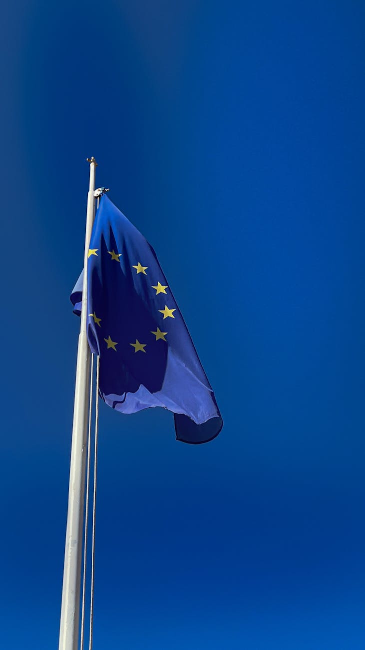 EU flag waving in a clear blue sky symbolizing unity and peace across member countries.