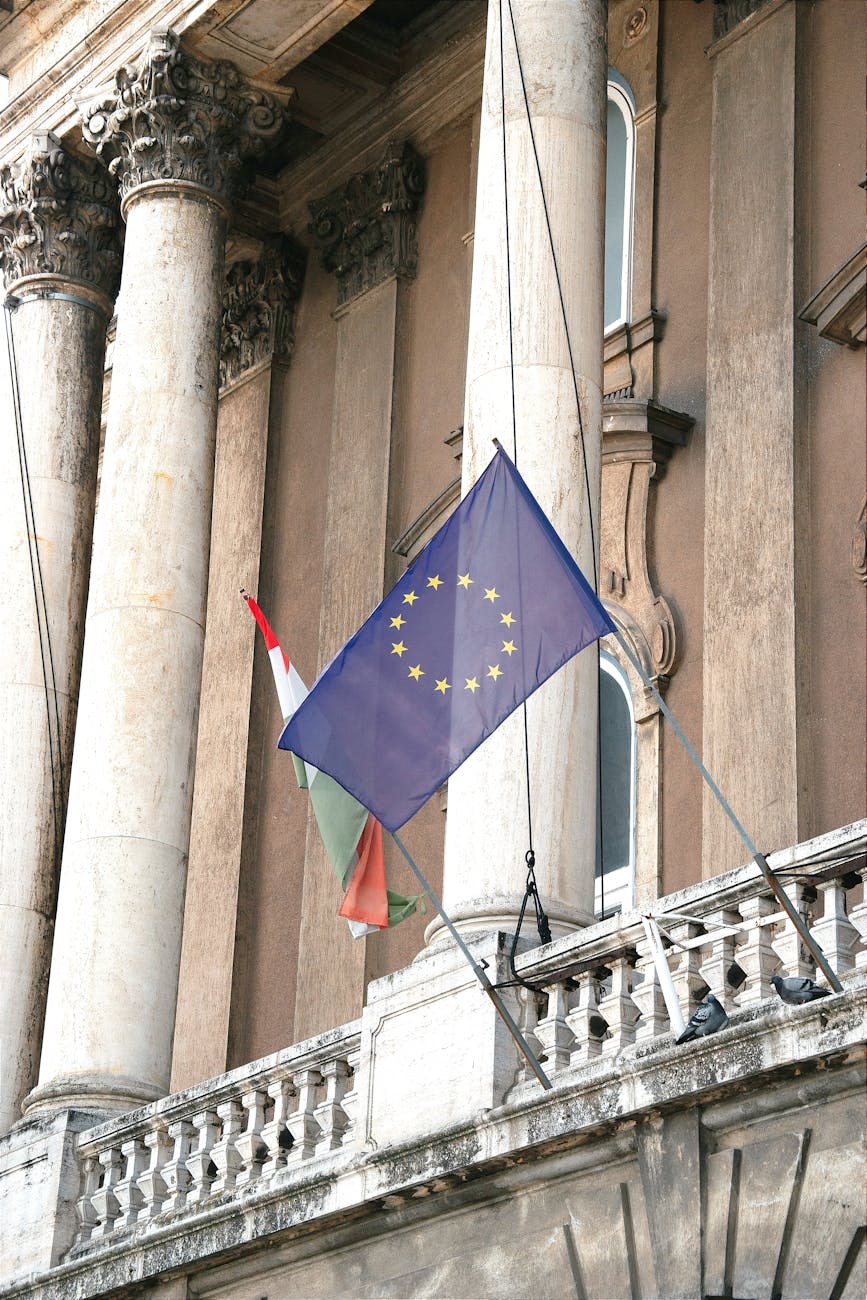 Flags of European Union and Hungary displayed on a historic building facade in Budapest, Hungary.