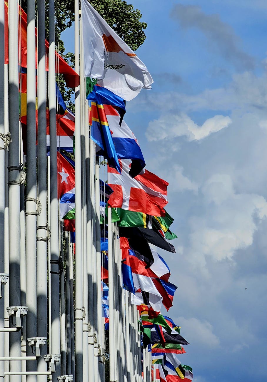 Colorful international flags fluttering in the wind against a blue sky in Lisbon, Portugal.