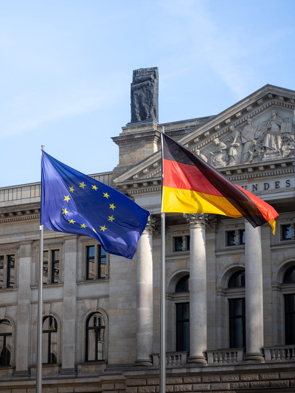 Flags of Germany and the European Union waving in front of the Bundestag building in Berlin, Germany.