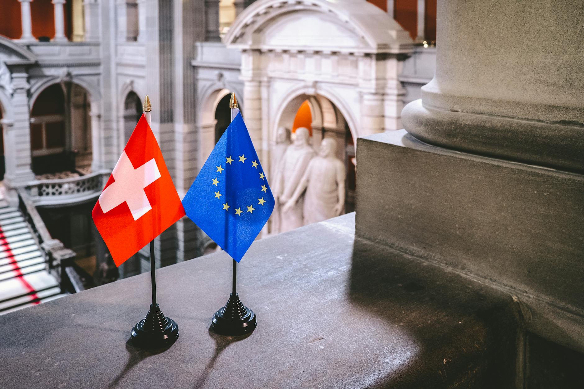 Swiss and EU flags on display inside a historical building in Bern, Switzerland.
