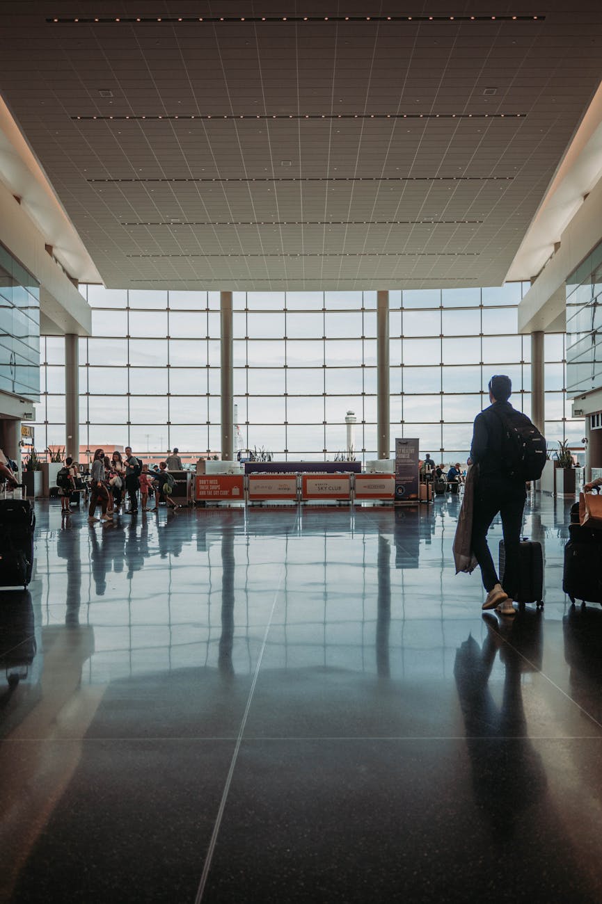 Busy airport terminal with travelers, luggage, and modern architecture.