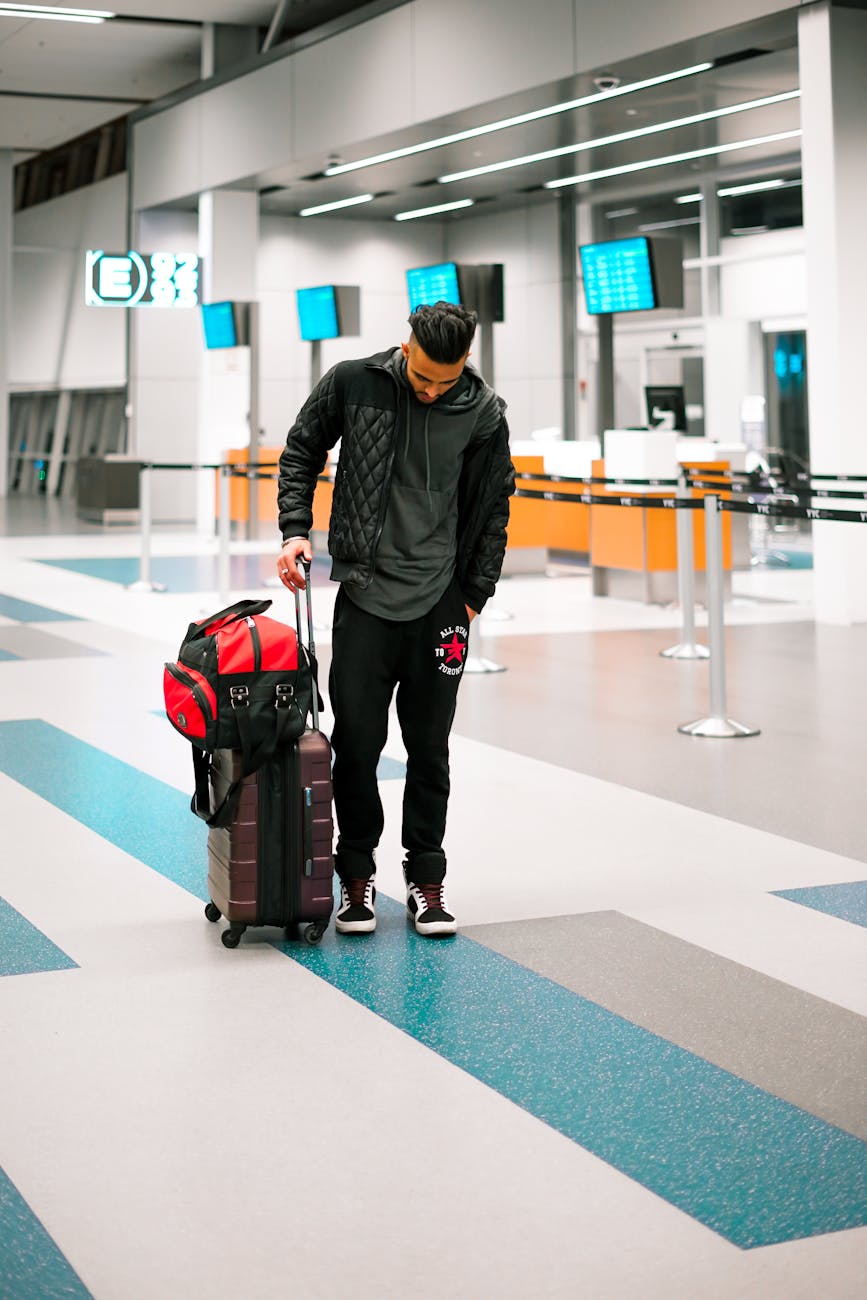 Man standing with luggage in a modern airport terminal, ready for travel.
