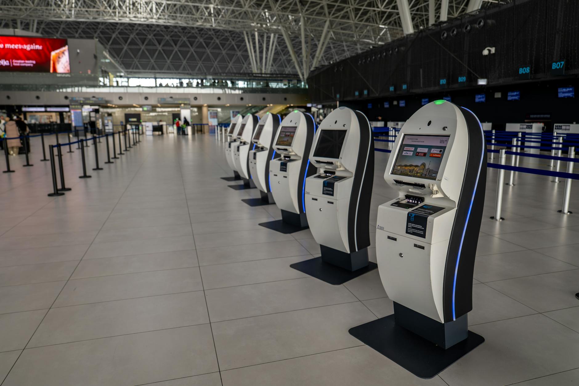 Wide view of an airport terminal in Zagreb featuring self-service check-in kiosks.