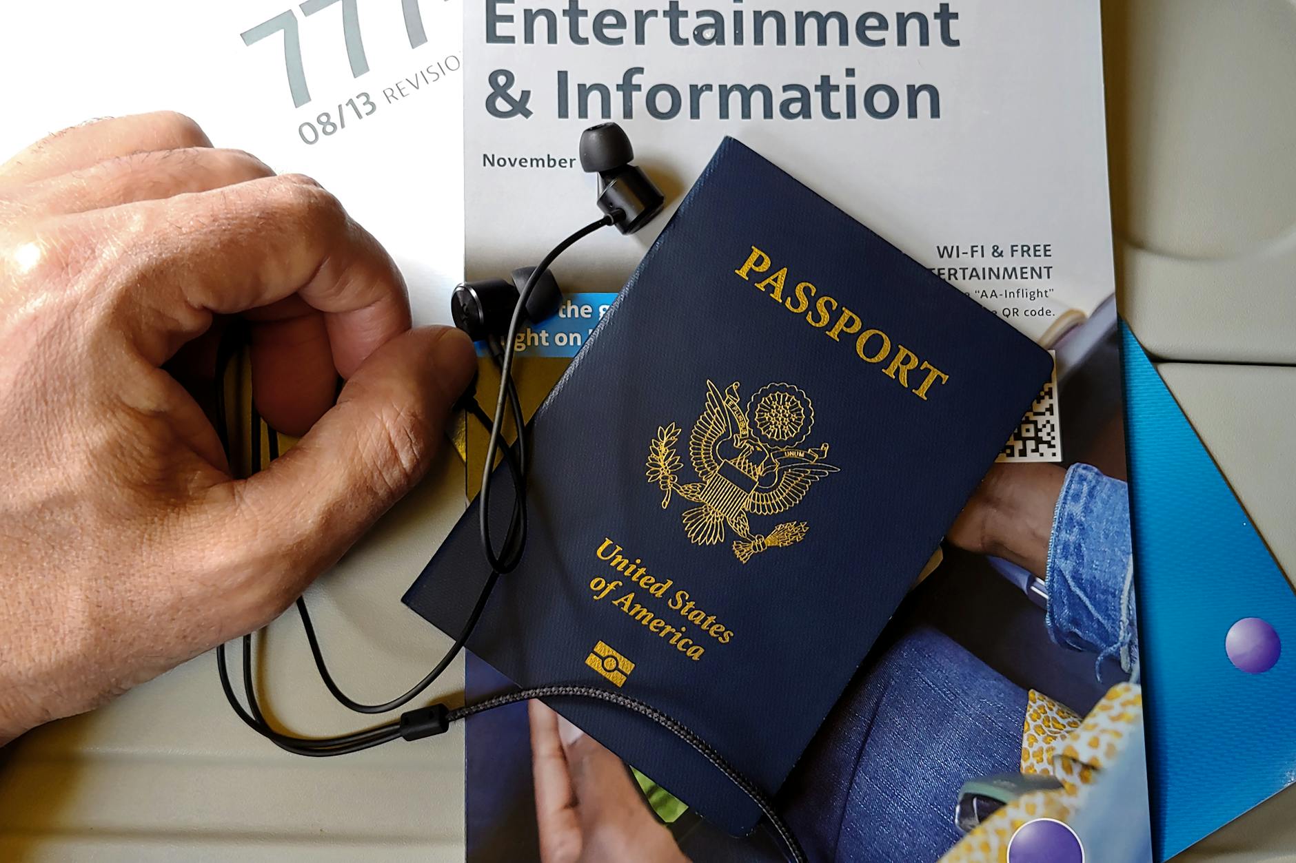 Close-up of US passport with inflight magazine and headphones on an airplane seat, ready for travel.
