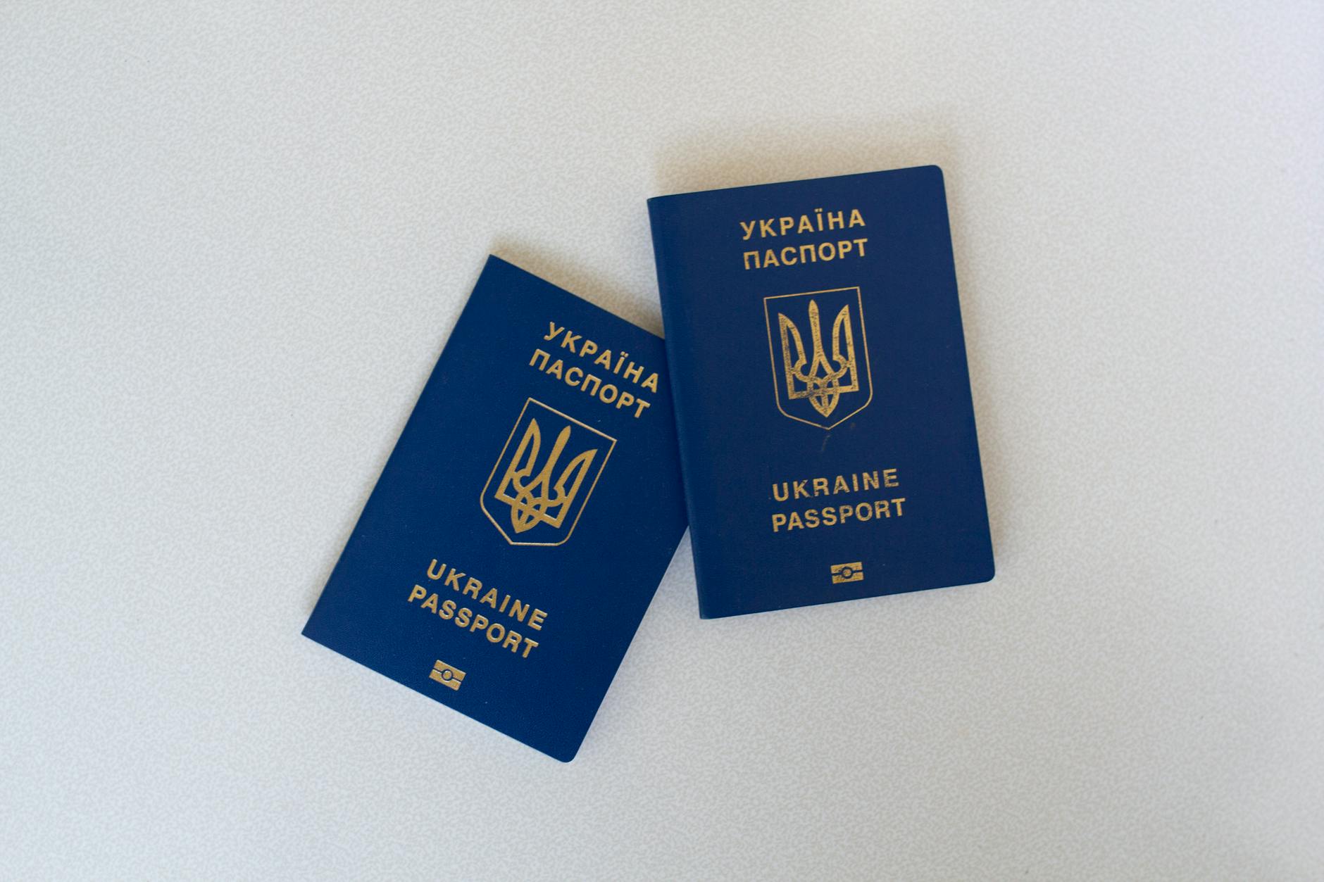 Two Ukrainian passports placed on a white surface in a flat lay style.