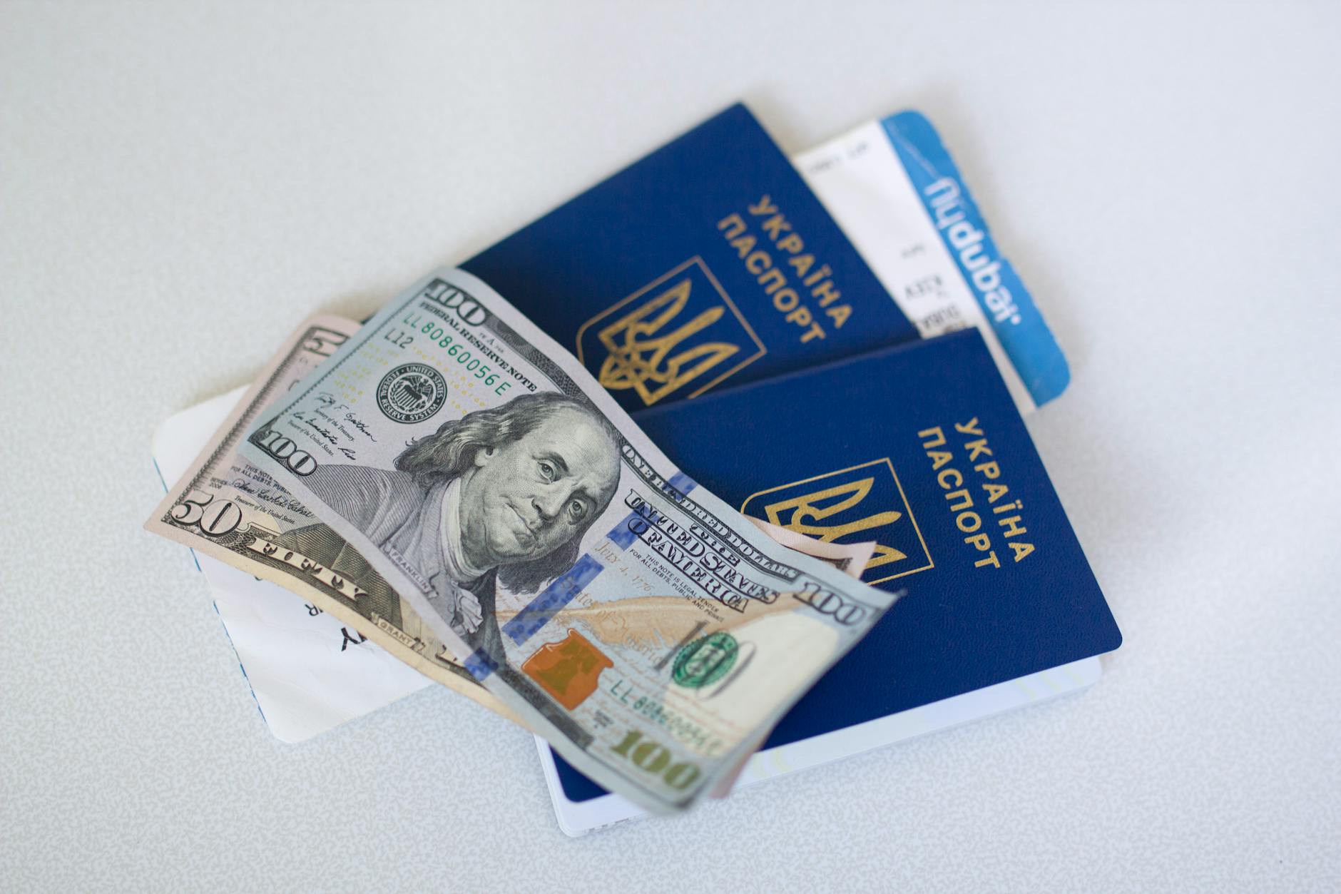 Close-up view of Ukrainian passports with US dollar bills, symbolizing travel readiness.