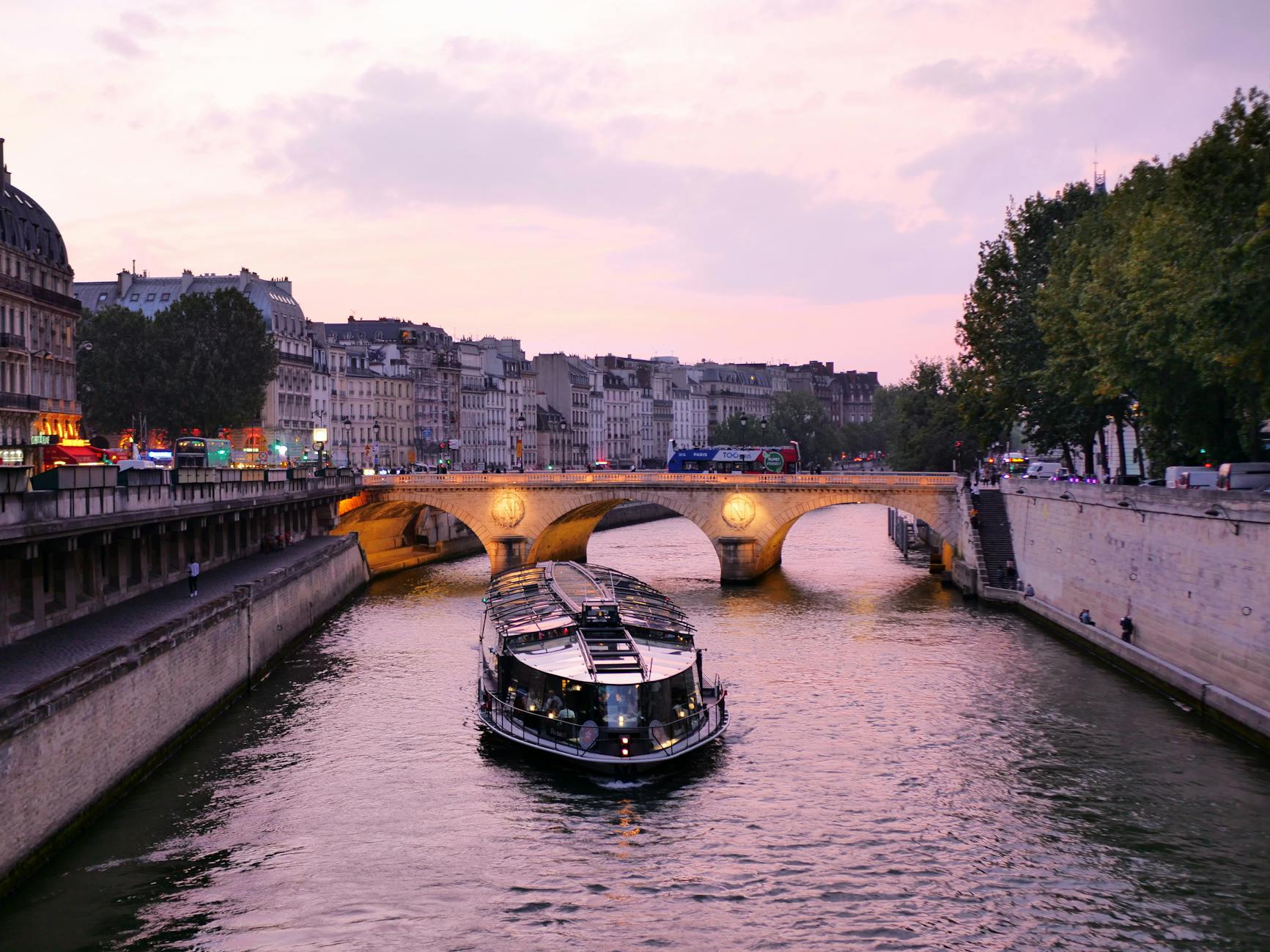A serene evening on the River Seine with a boat and historic Parisian architecture in view.