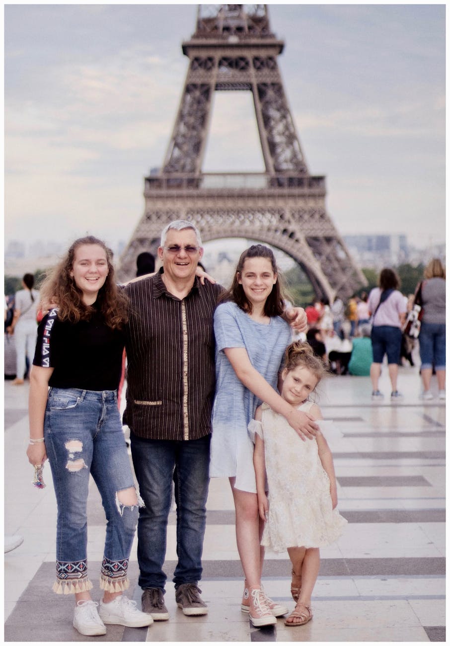 A happy family posing in front of the iconic Eiffel Tower in Paris, France.