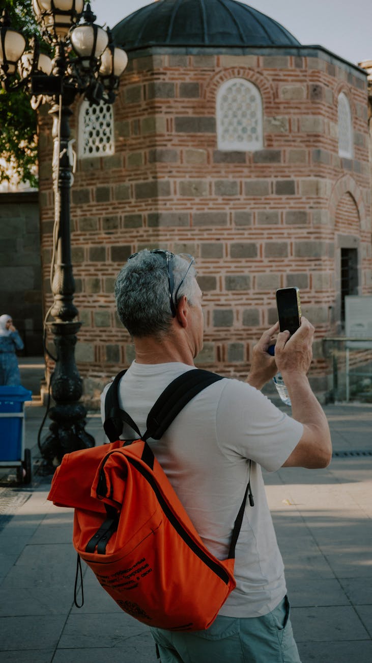 Middle-aged tourist takes photo of historic building with smartphone.