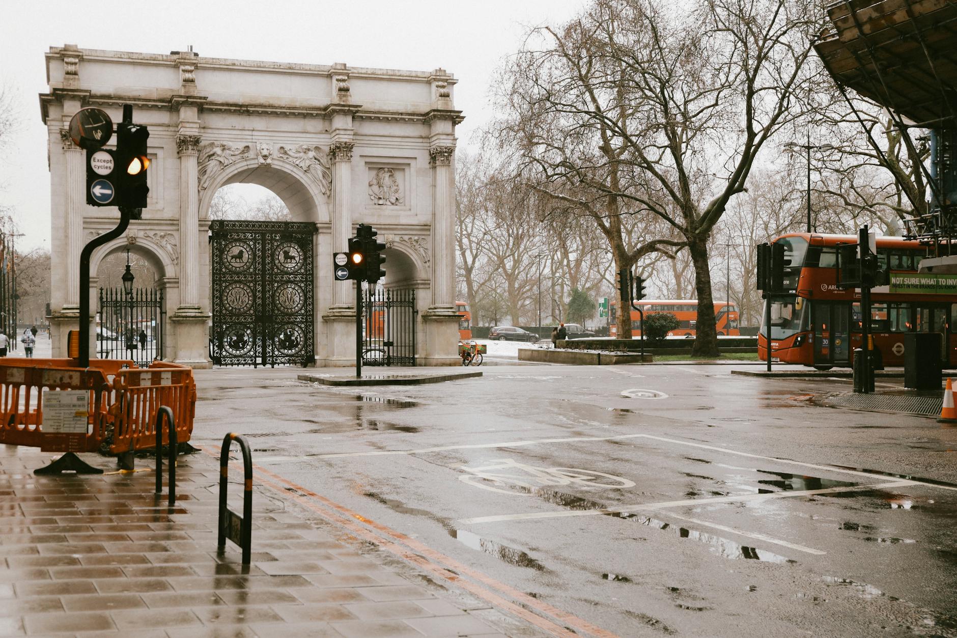 View of London’s Marble Arch and city buses on a rainy day, reflecting urban morning commute.