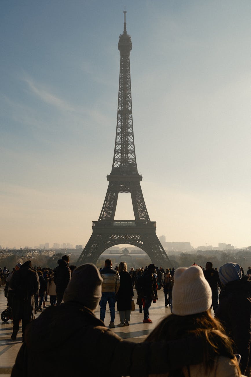 Tourists admire the iconic Eiffel Tower in Paris, France on a sunny day.