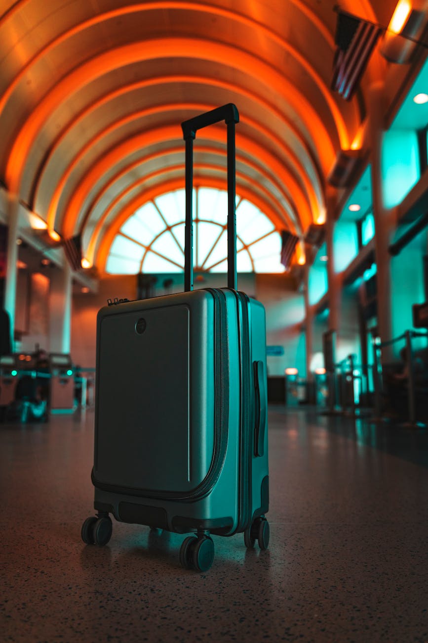 A modern suitcase in a vibrant airport terminal evokes travel excitement.