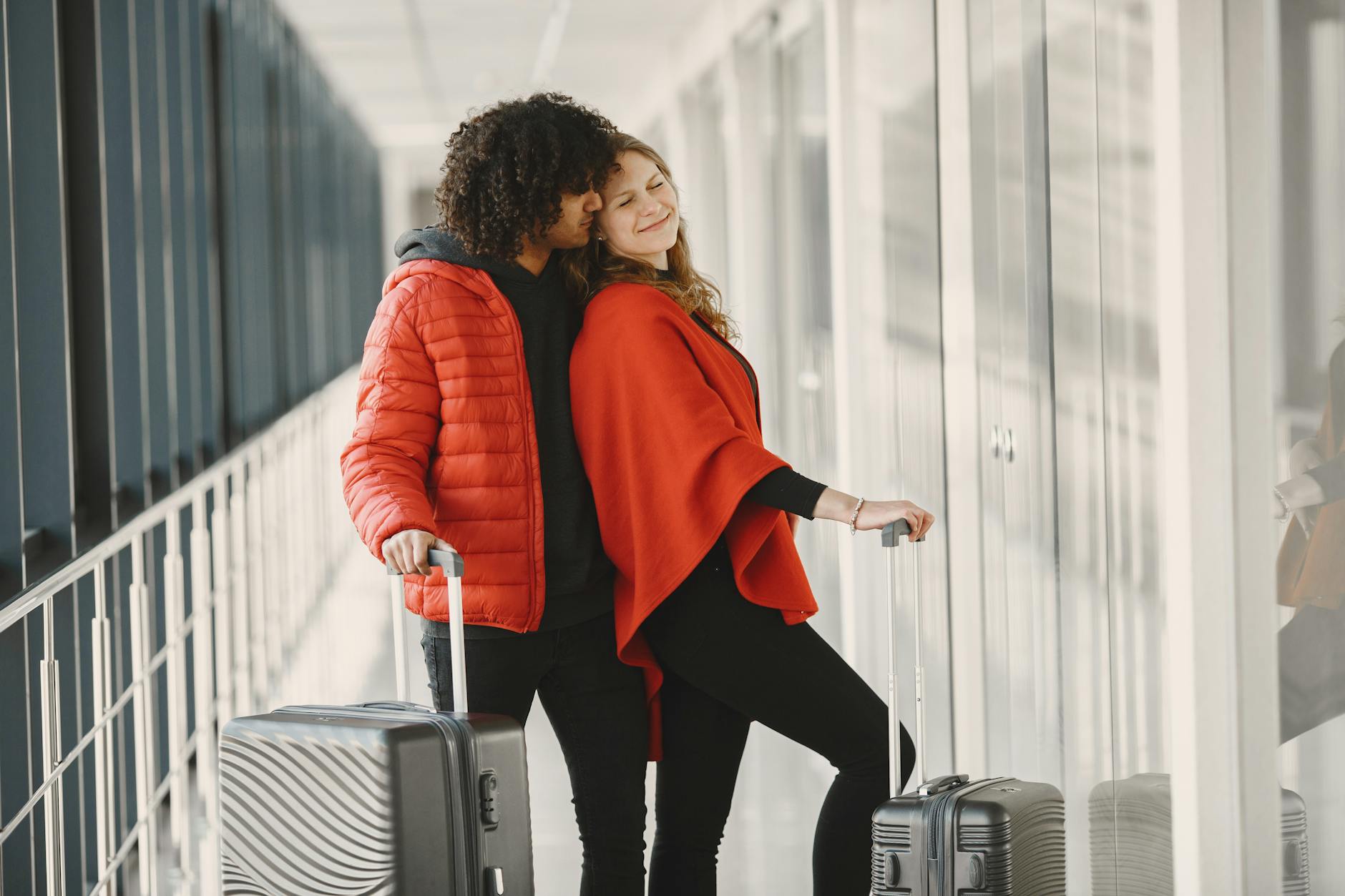 Smiling couple standing with luggage in an airport corridor, enjoying their journey.