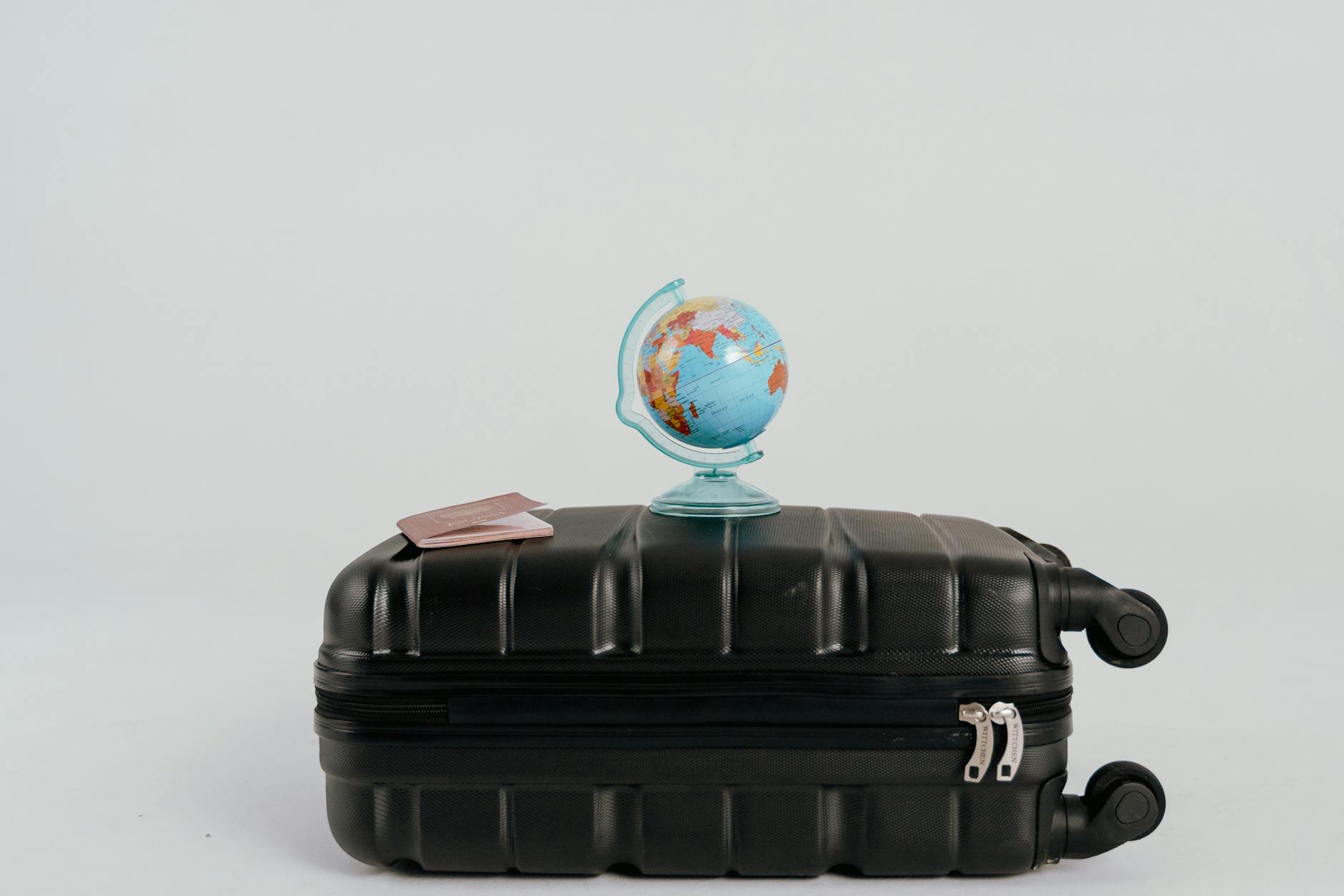 A globe placed on a black suitcase symbolizing global travel and adventure.