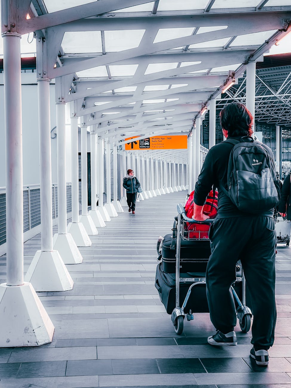 Travelers with luggage trolleys navigating through Dortmund Airport's terminal walkway.