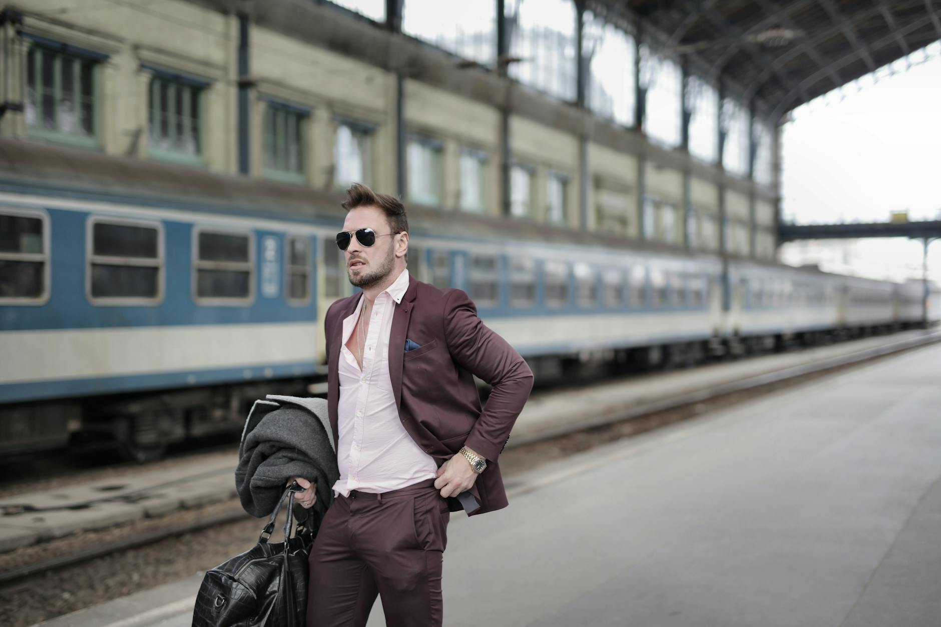 Stylish man in a suit waiting at a platform, embodying confidence and professionalism.