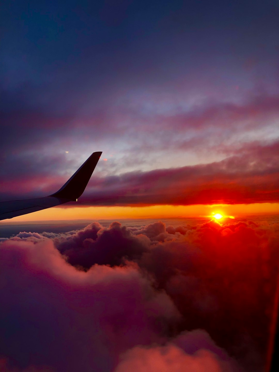 airplane wing over clouds during sunset